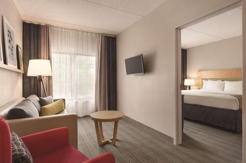 a hotel room with a bed and a couch and a chair at Country Inn & Suites by Radisson Raleigh-Durham Airport NC in Morrisville