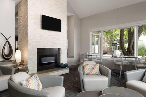 a living room with chairs and a fireplace at Eastland Suites Hotel & Conference Ctr, Trademark by Wyndham in Bloomington