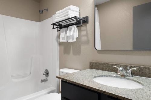 a bathroom with a sink and a mirror at Eastland Suites Hotel & Conference Ctr, Trademark by Wyndham in Bloomington