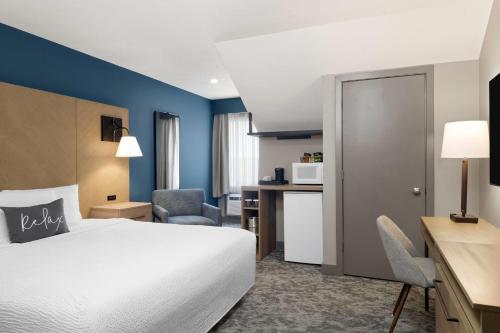 a hotel room with a bed and a desk at Eastland Suites Hotel & Conference Ctr, Trademark by Wyndham in Bloomington