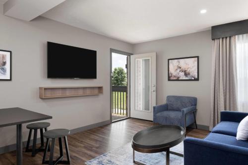 a living room with a flat screen tv on a wall at Eastland Suites Hotel & Conference Ctr, Trademark by Wyndham in Bloomington