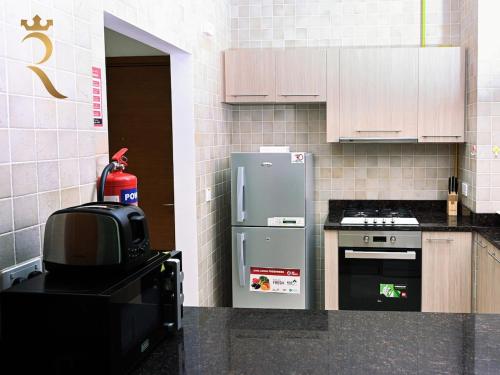 a small kitchen with a refrigerator and a stove at Supernova Haven 1BR - Peaceful Poolside Getaway Near Yas Mall & Marina in Abu Dhabi