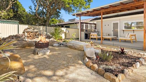 a patio with a fire pit in a yard at Cute Beach Cottage - Absolute Beach Front in Toukley