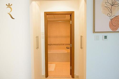 a bathroom with a door leading to a bath tub at Supernova Haven 1BR - Peaceful Poolside Getaway Near Yas Mall & Marina in Abu Dhabi