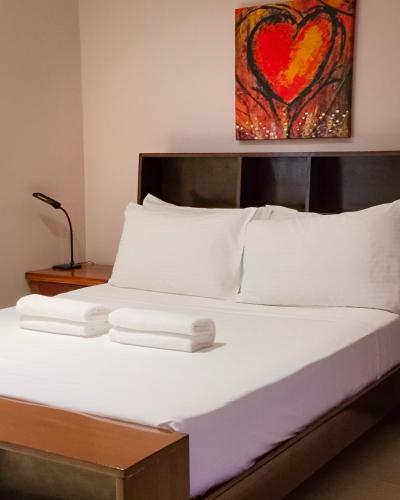a bed with white pillows and a heart painting on the wall at Reef Beach Resort in General Luna