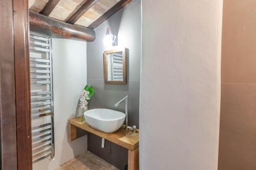 a bathroom with a white sink on a wooden counter at Respiro Umbria, 1500s Villa with Unique Biopool in Spoleto