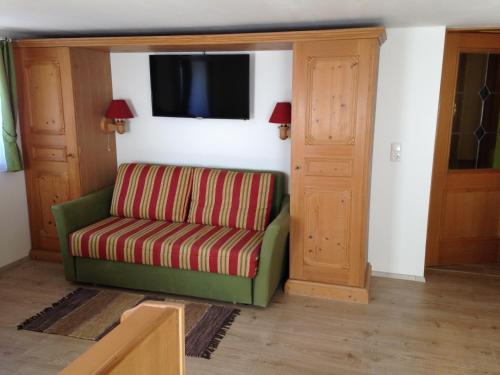 a living room with a green chair and a television at Haus Julia in Mühlbach am Hochkönig