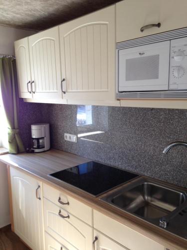 a kitchen with white cabinets and a sink and a microwave at Haus Julia in Mühlbach am Hochkönig
