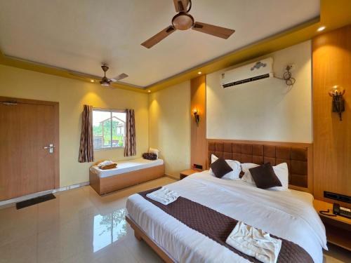 a bedroom with a large bed with a ceiling fan at Relax Adventure Resort in Igatpuri