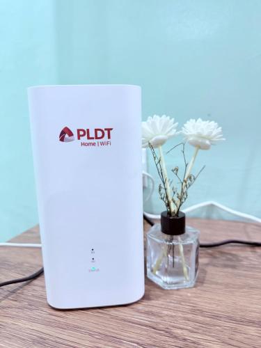 a white router sitting on a table with a vase of flowers at Chic 4BR 15 Pax Euro-Inspired Home, Malolos in Malolos