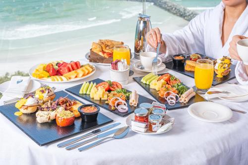 アジュマーンにあるAjman Saray, a Luxury Collection Resort, Ajmanの食べ物と飲み物がいっぱいのテーブルと食べ物が置かれたテーブル