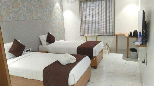 a hotel room with two beds and a television at The Monarch Hotel Bagalur IT Park in Bengaluru