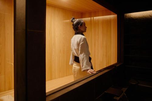 a woman is standing in a walk in shower at Cave Ryokan Hotel by Aank Sungshin Women's University in Seoul