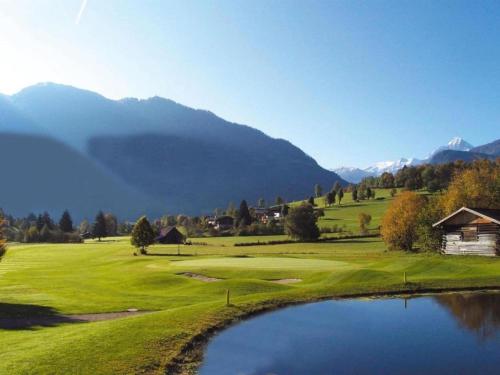 a golf course with a pond and mountains in the background at Chalet in Königsleiten by Zillertal Ski Arena in Wald im Pinzgau