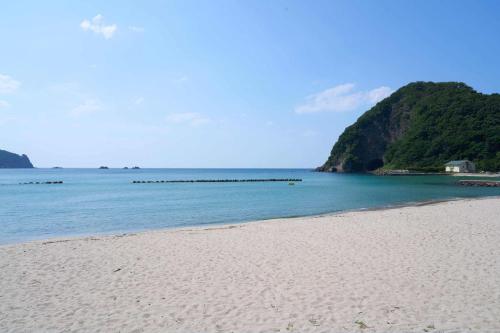 a sandy beach with a view of the ocean at Yodoya in Toyooka