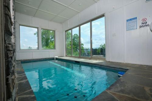a swimming pool with blue water in a room with windows at Whitneys Way in Gatlinburg