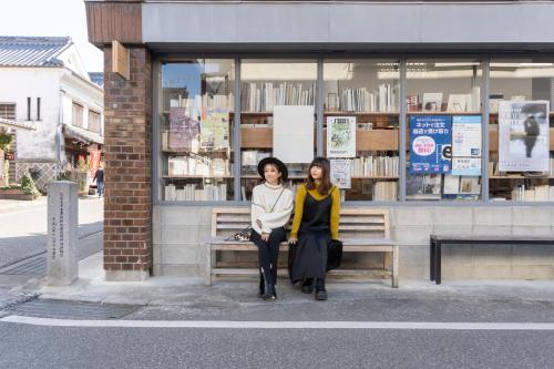 two women sitting on a bench in front of a bookstore at Kiyonoya in Asakura