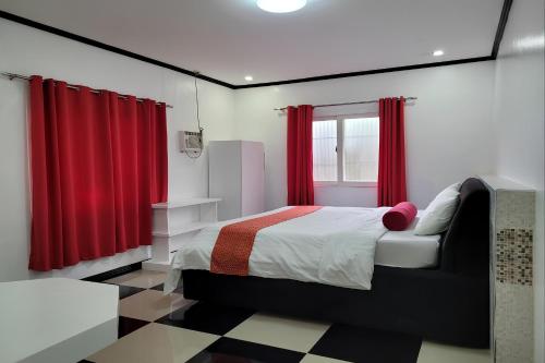 a bedroom with a bed with red curtains and a checkered floor at Jewelry Resort and Villas Tagaytay in Silang