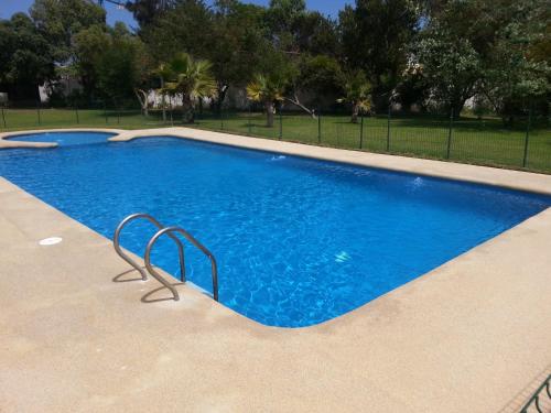 a swimming pool with blue water in a park at Stellamar Apart Hotel in La Serena