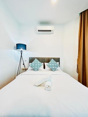 a bedroom with a white bed with a blue lamp at LESTARI INN RESIDENCE in Kuantan