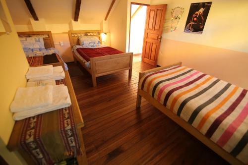 a small room with two beds and wooden floors at Casa Verde Hostal in Sucre
