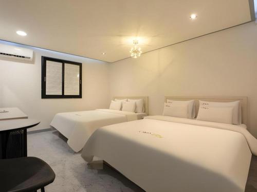 a bedroom with two beds and a desk and a table at Chuncheon World Hotel in Chuncheon