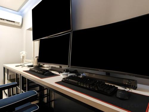 a desk with two computer monitors and a keyboard at Chuncheon World Hotel in Chuncheon