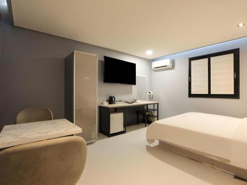 a bedroom with a bed and a desk with a television at Chuncheon World Hotel in Chuncheon