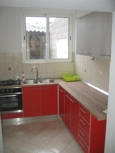 a kitchen with red cabinets and a sink and a window at Nevera Apartments Pašman,Banj in Banj