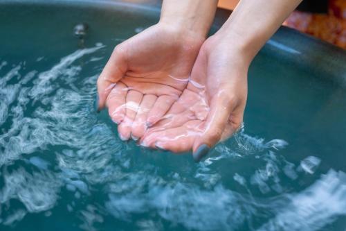 a person washing their hands in a pool of water at Kiyonoya in Asakura