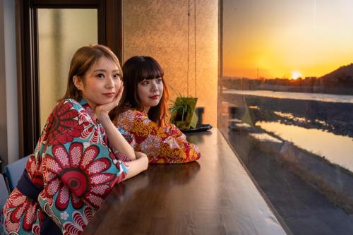 two girls sitting on a counter looking at the camera at Kiyonoya in Asakura