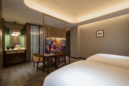 a hotel room with a bed and a desk at Xiamen Lujiang Harbourview Hotel in Xiamen