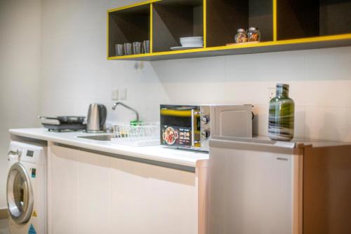 a kitchen with a white counter top and a dishwasher at Arte Plus KLCC Designer Suites by Cobnb in Kuala Lumpur