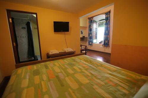 a bedroom with a bed and a mirror and a television at Casa Verde Hostal in Sucre