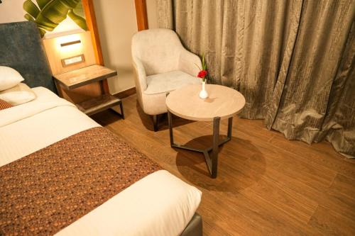 a bedroom with a bed and a chair and a table at Menaka inn in Dhārwād
