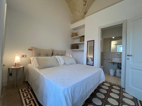 a bedroom with a white bed with a lamp on a table at La Torretta dimora storica in Montesano Salentino