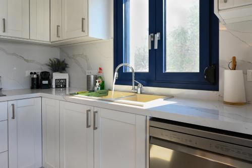 a kitchen with white cabinets and a sink and a window at Ifigenia VIlla Sissi in Sissi