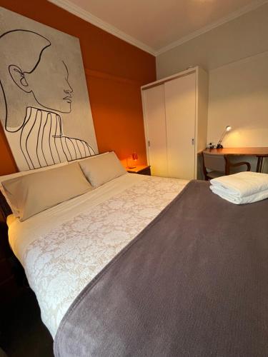 a bedroom with a large bed with a painting on the wall at Room @ 88 in Devonport