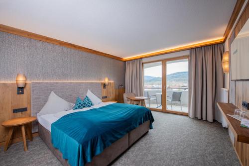 a hotel room with a bed and a large window at Hotel Königgut in Wals