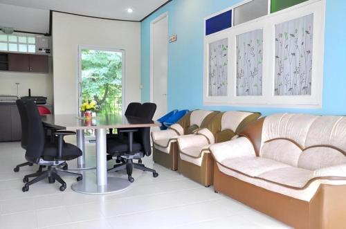a waiting room with couches and a table and chairs at At Home Suanphung in Ratchaburi