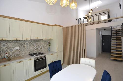 Una cocina con gabinetes blancos y una mesa y sillas azules. en Daren Apartment, en Eforie Nord