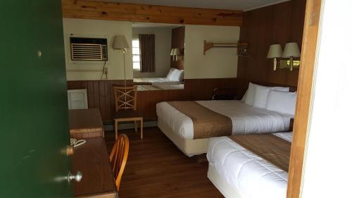 a hotel room with two beds and a table at Budget Host Inn in Detroit Lakes