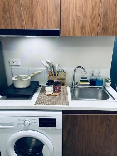a kitchen with a sink and a washing machine at J&J Mactan Stays with Netflix, Pool & Paid Parking in Suba