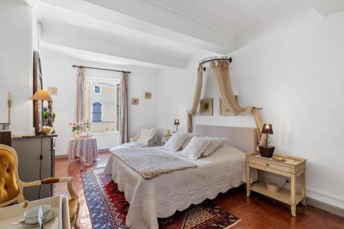 a white bedroom with a bed and a chair at L'ORANGERIE Chambres d'hotes de charme in Valros
