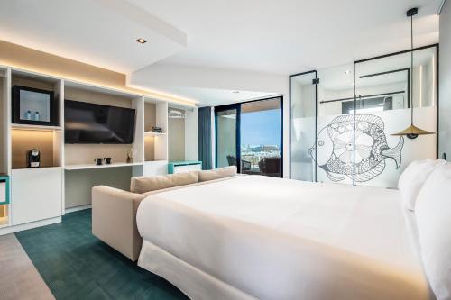 a bedroom with a large white bed and a couch at Hotel Puerto de la Luz by Pierre & Vacances in Las Palmas de Gran Canaria