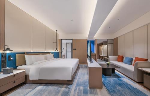 a bedroom with a large white bed and a couch at Novotel Hangzhou Yuhang in Yuhang