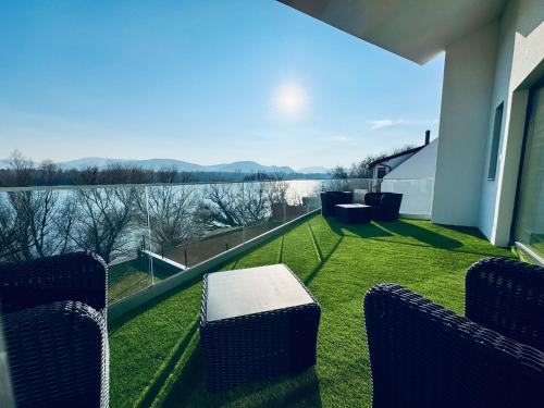 a balcony with chairs and a view of the water at Duna Corner Panzió in Verőce