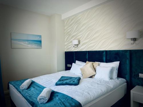 a bed with a blue headboard and pillows on it at Duna Corner Panzió in Verőce