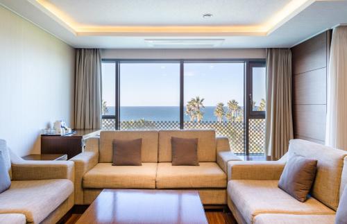 a living room with a couch and a view of the ocean at Uni Hotel Jeju in Jeju