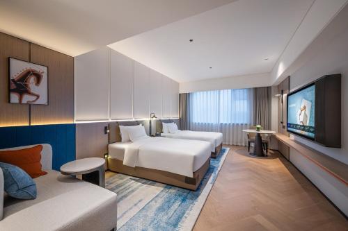 a hotel room with two beds and a tv at Novotel Hangzhou Yuhang in Yuhang
